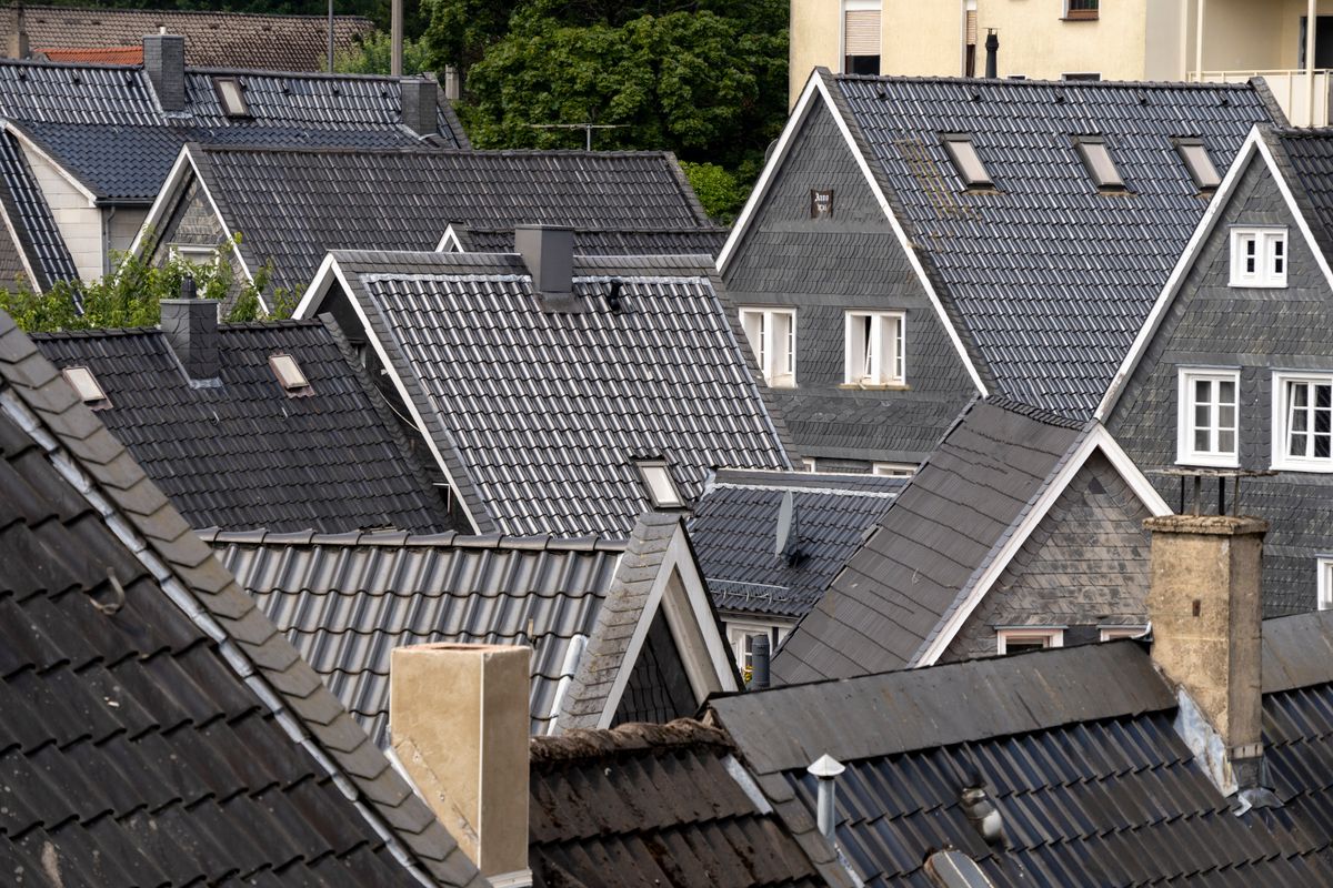 Slate and tile rooftops with several chimney pots and stacks in a residential neighbourhood
